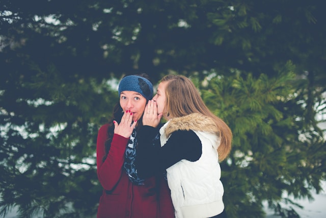 woman-whispering-on-womans-ear-while-hands-on-lips-ben-white
